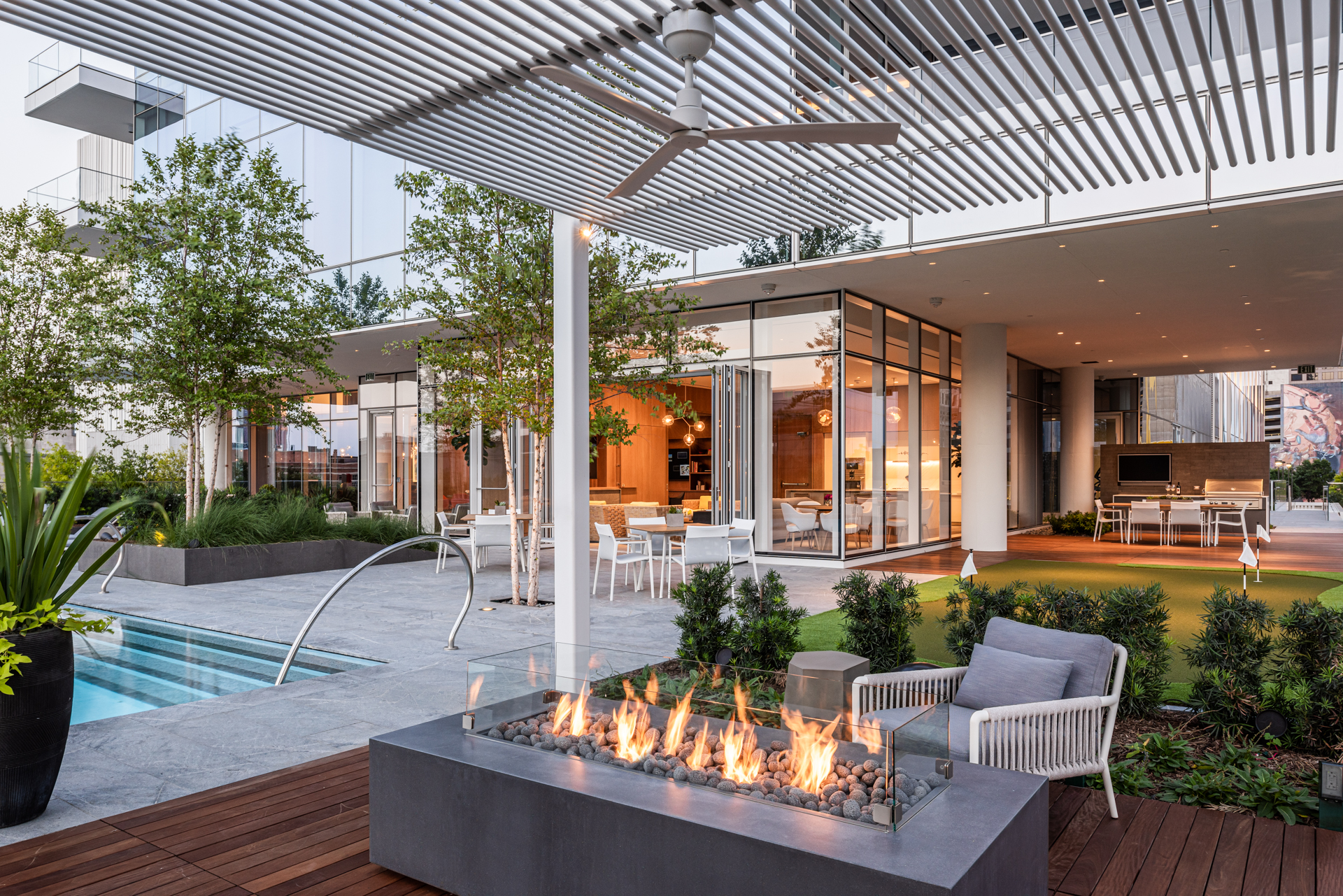 Amenity deck with modern fire pit, grill, and pool.