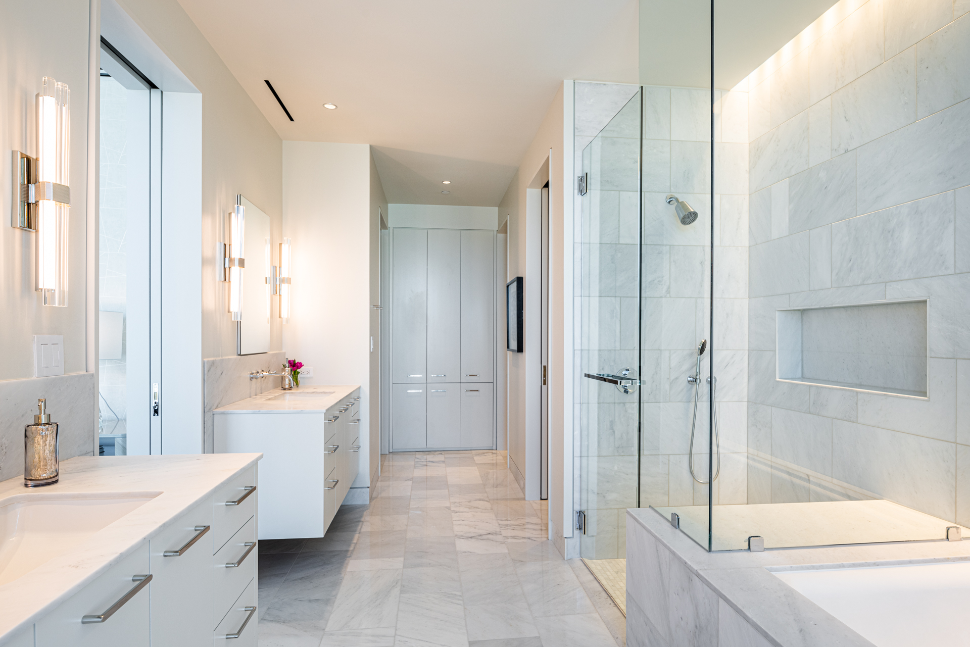 White bathroom with walk in shower and double sinks.