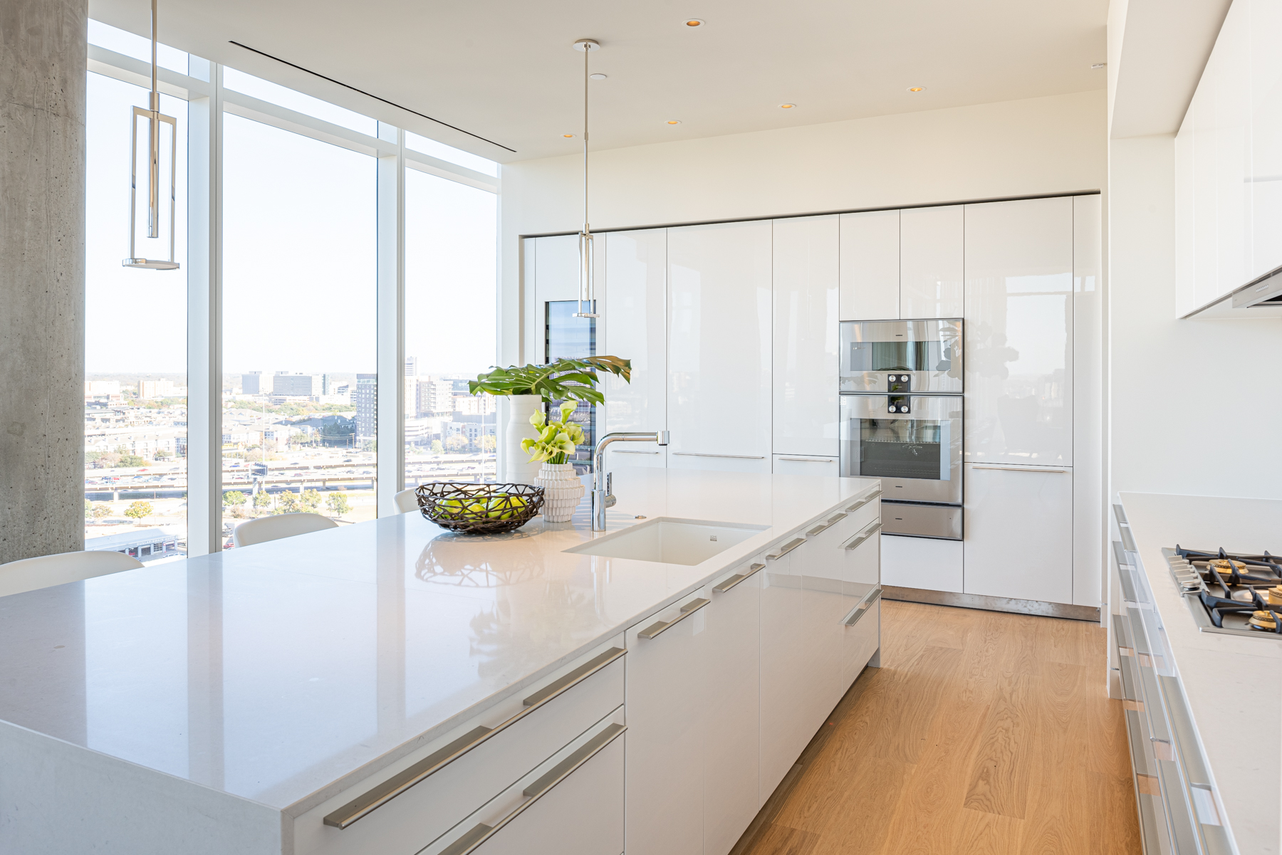 Modern white kitchen with light grey stainless steel appliances.