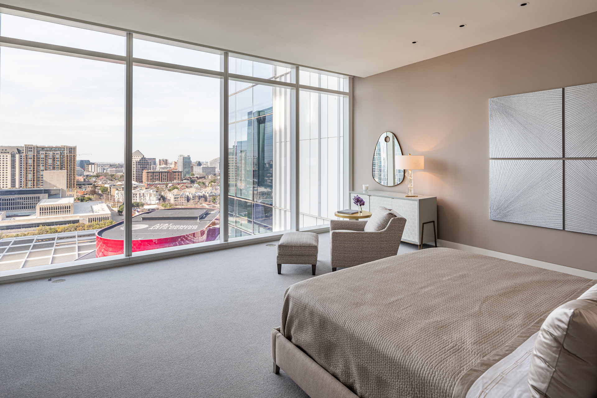 Bedroom with cream furniture and floor to ceiling windows overlooking Winspear Opera House.