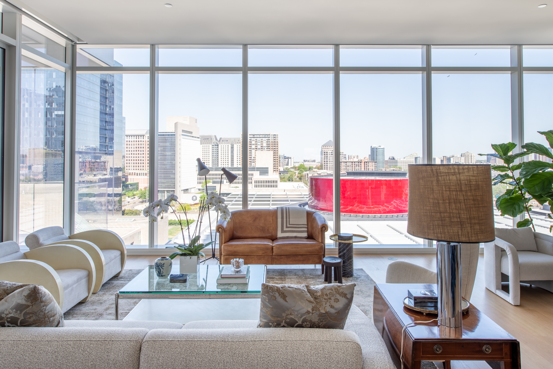 Living room with nude furniture and view of Winspear Opera House.