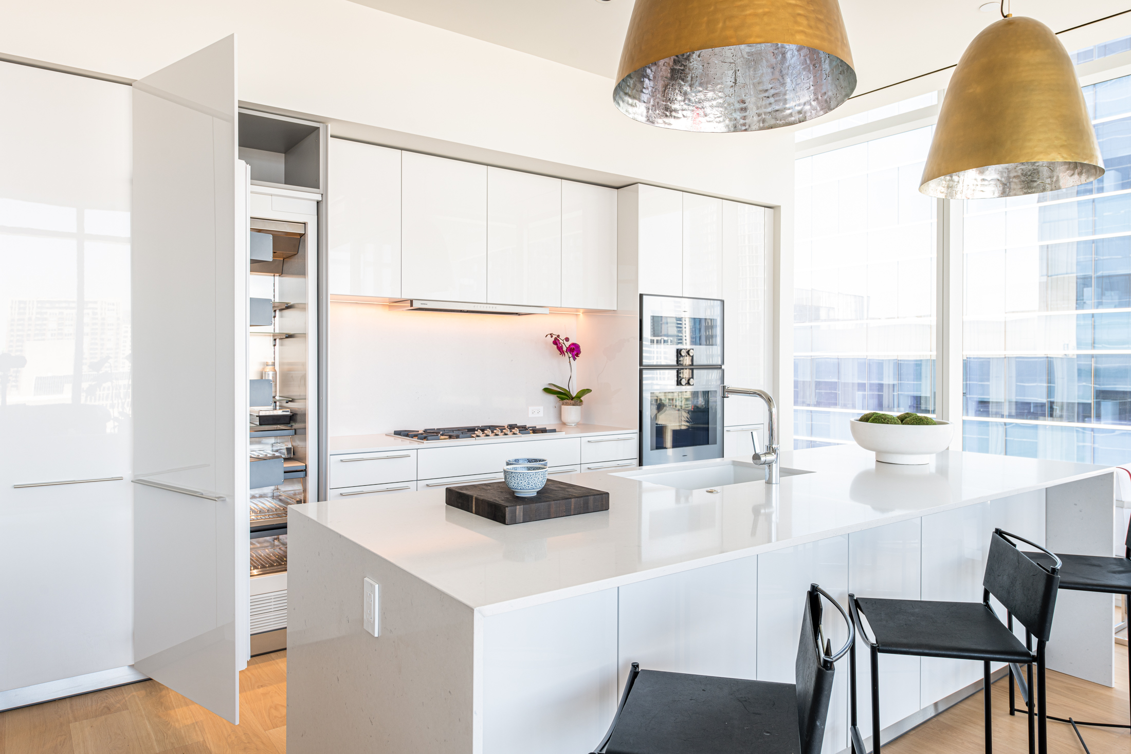 White modern kitchen with chilled wine pantry and island.